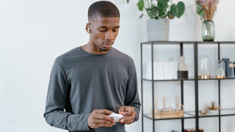 Young african american man looking at his phone in the living room.